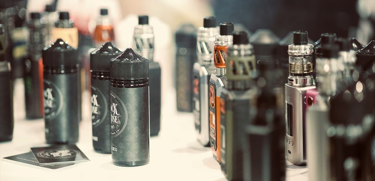 Collection of vape devices and e-liquid bottles displayed on a table featuring zero nicotine disposable vape options.