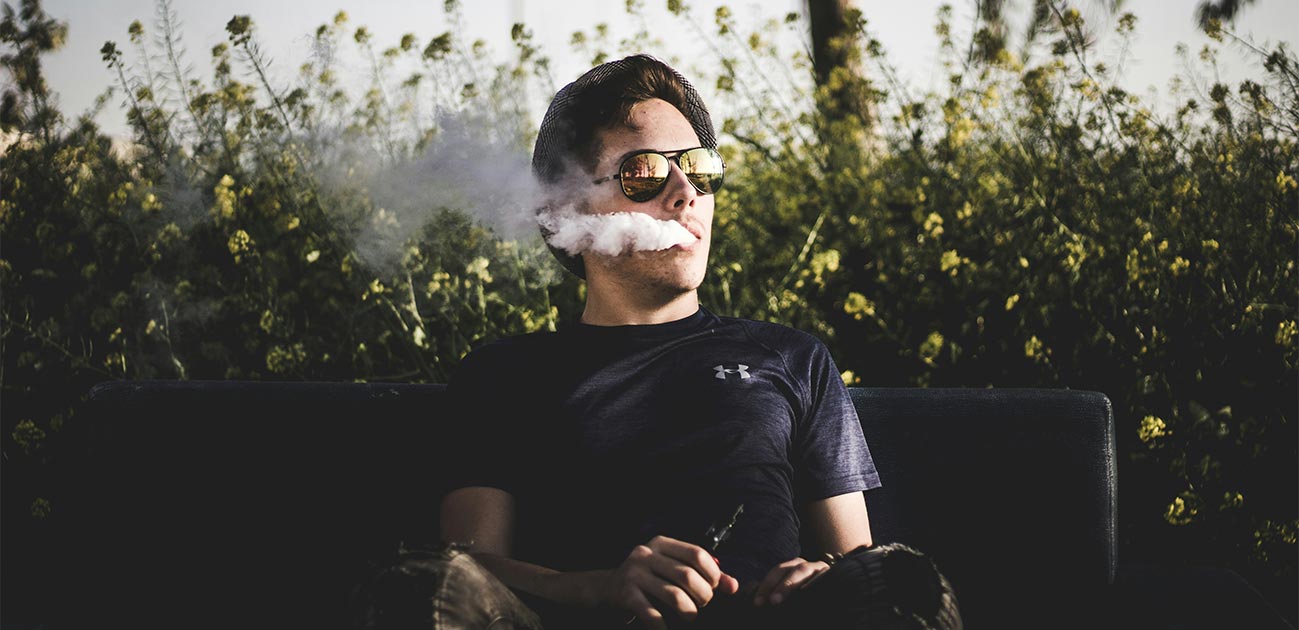 Person using a zero nicotine vape outdoors with visible vapor cloud