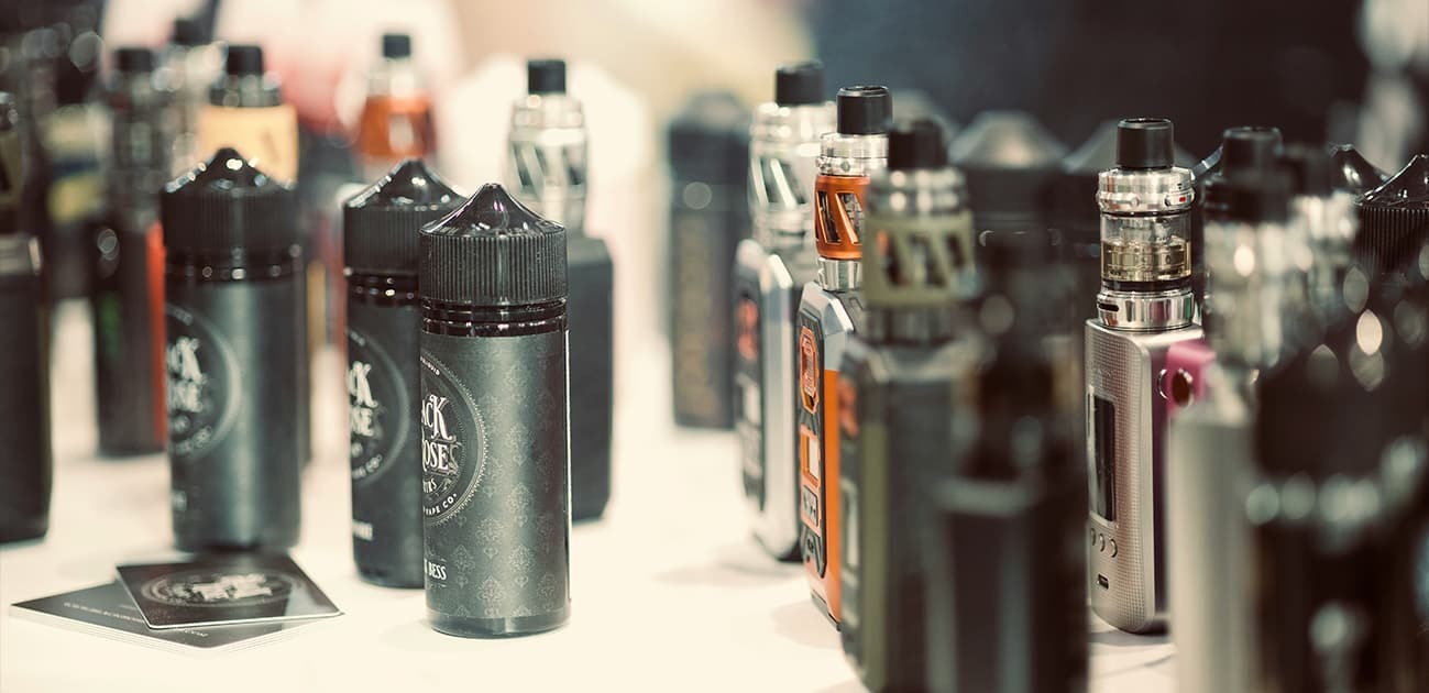 Collection of vape devices and e-liquid bottles displayed on a table featuring zero nicotine disposable vape options.